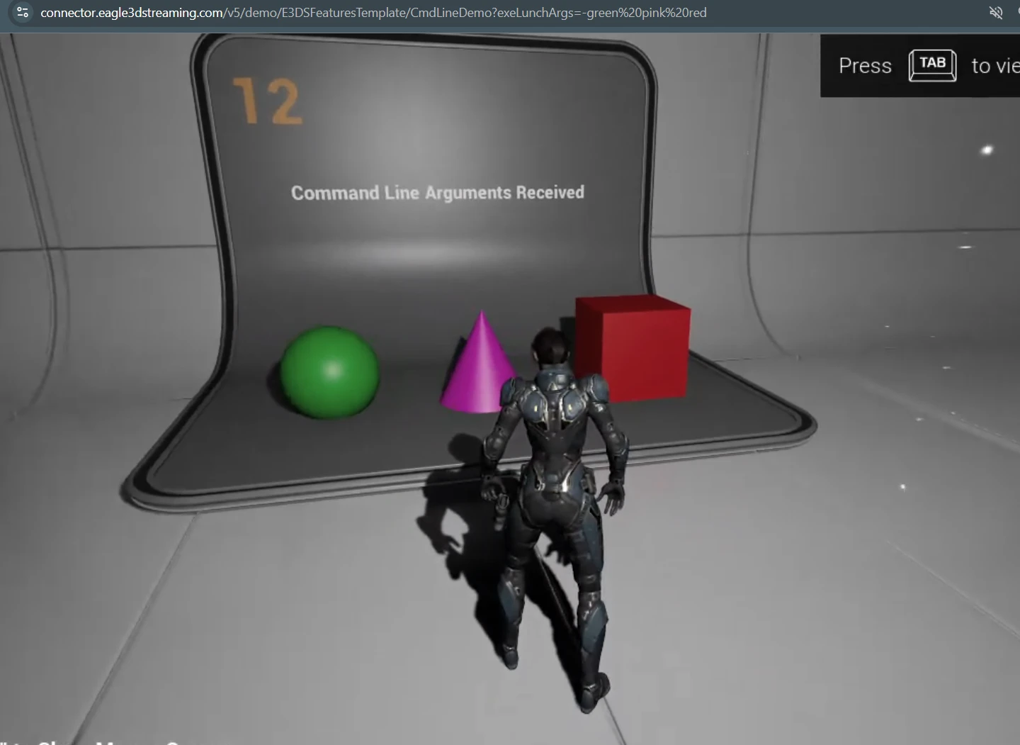 The demo at booth 12 with a green ball, pink cone and red box, and the browser address bar showing a link that contains only colours and no booth number